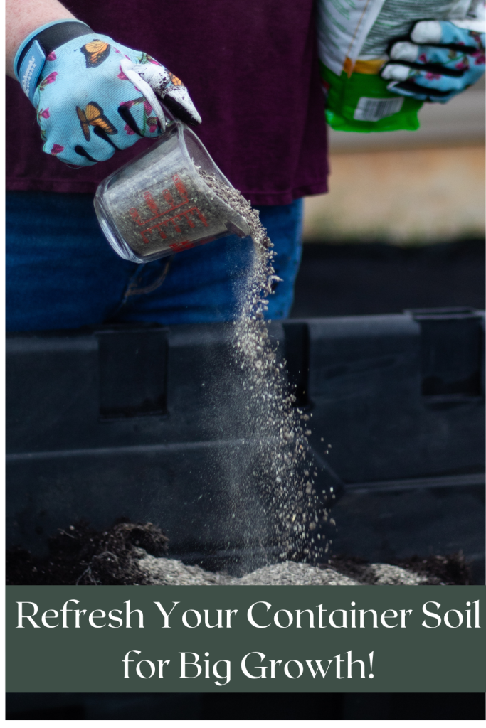 Close-up of a person pouring soil amendment from a measuring cup into a garden container while wearing butterfly-patterned gloves.