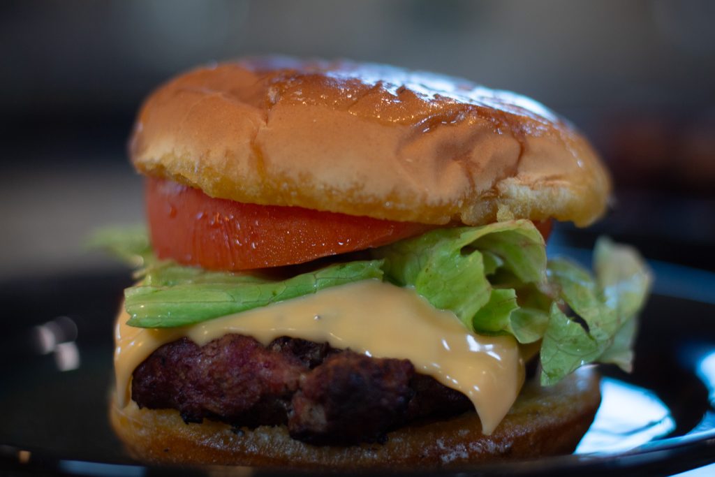 Close-up of a fully assembled lion’s mane burger with lettuce, tomato, and cheese.