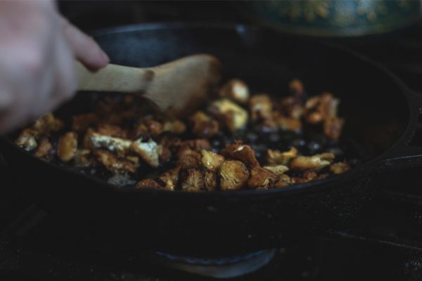 Lion’s mane mushrooms cooking in a cast iron skillet with a wooden spoon.
